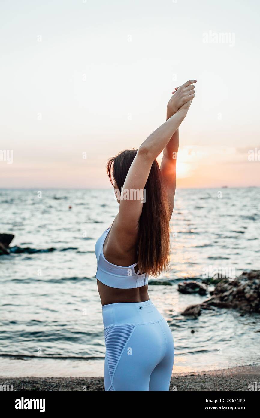 Vue latérale d'une jeune femme debout dans un poste de yoga Warrior sur une plage de sable Banque D'Images