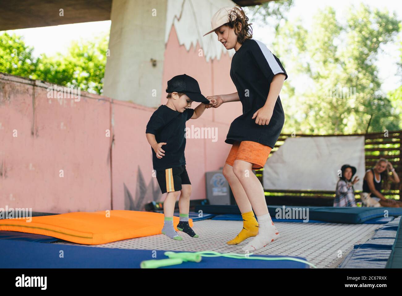 Les enfants d'origine caucasienne sautent ensemble sur un trampoline. Deux frères s'amusent sur un trampoline tenant les mains. Enfants sautant sur un trampoline à l'extérieur Banque D'Images
