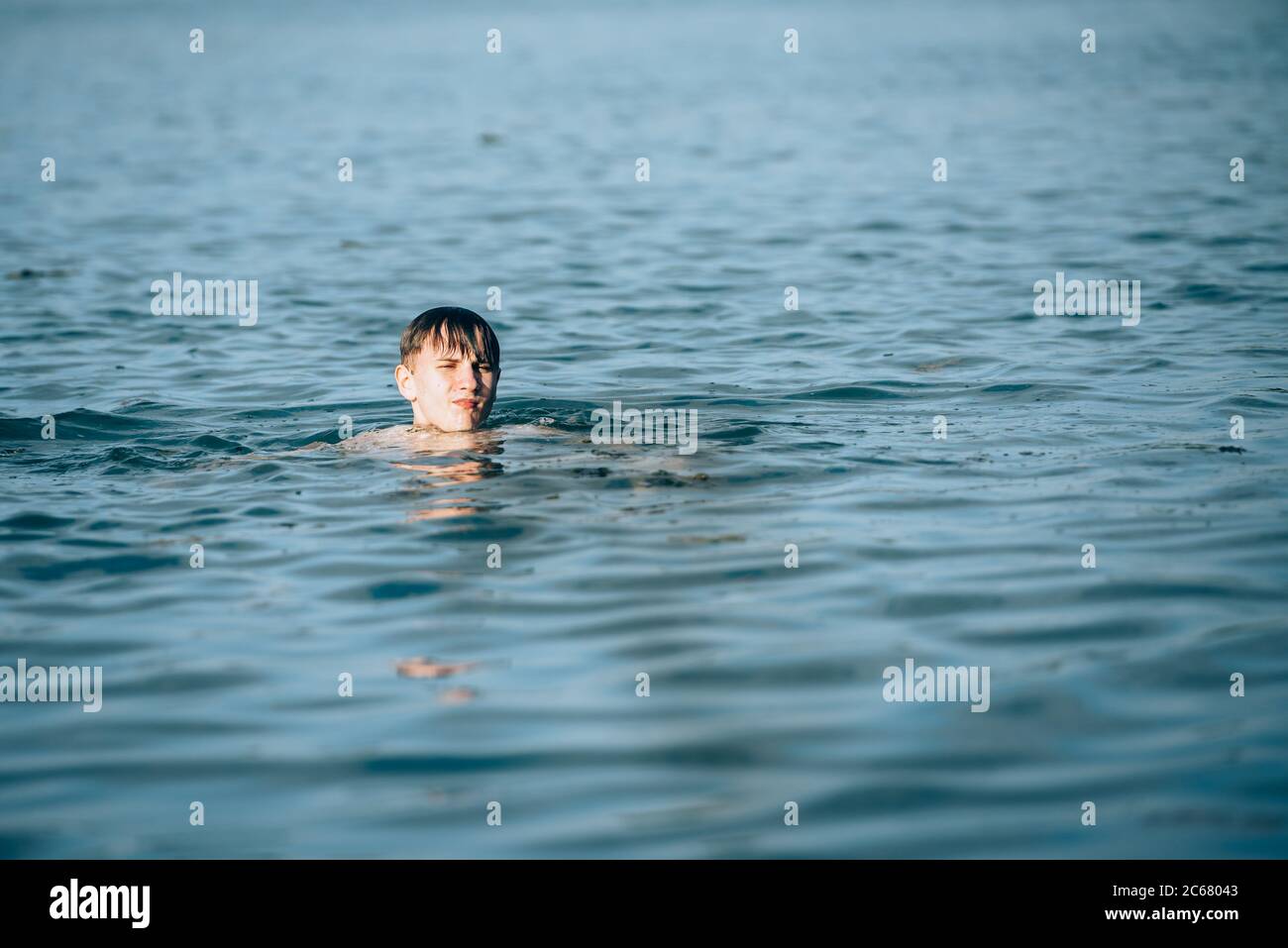 Garçon nageant dans le lac en été-vue de l'arrière Banque D'Images