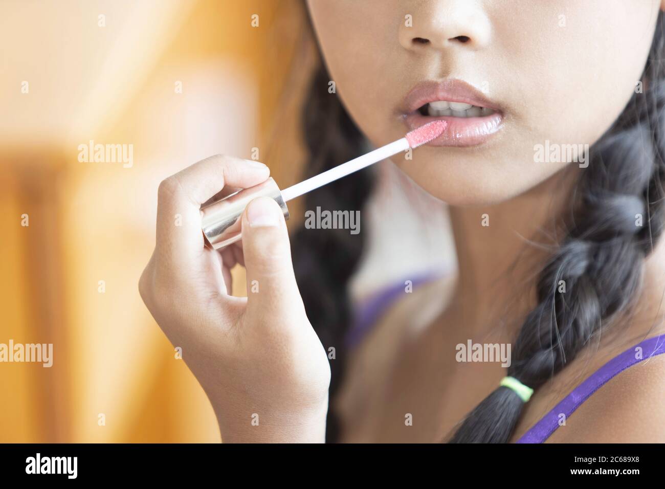 Une jeune fille asiatique à cheveux longs est en utilisant le rouge à lèvres pour appliquer le maquillage de lèvres pendant une leçon de maquillage. Banque D'Images