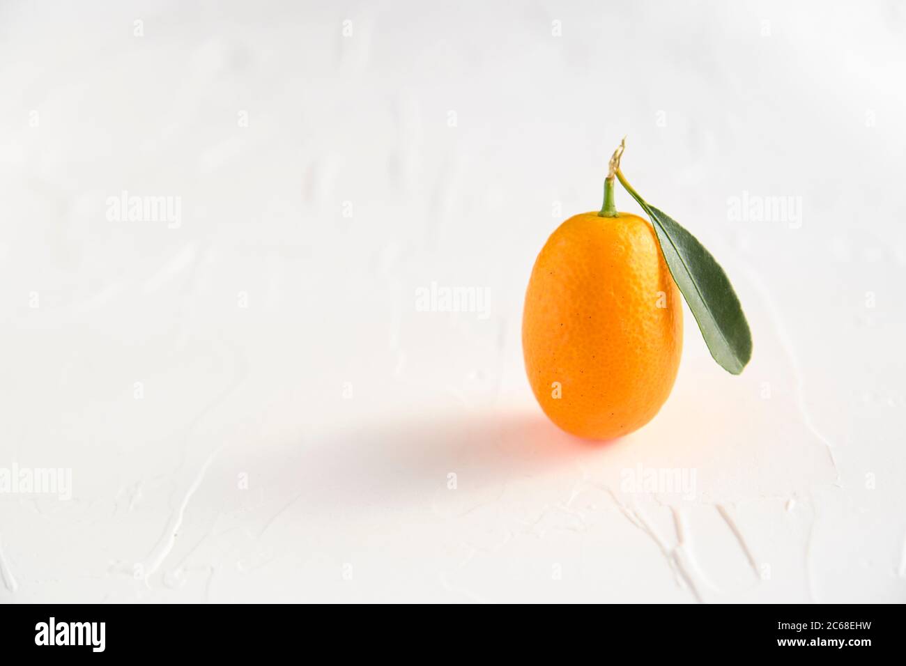 Un kumquat, un petit fruit exotique aux agrumes, avec sa feuille, sur