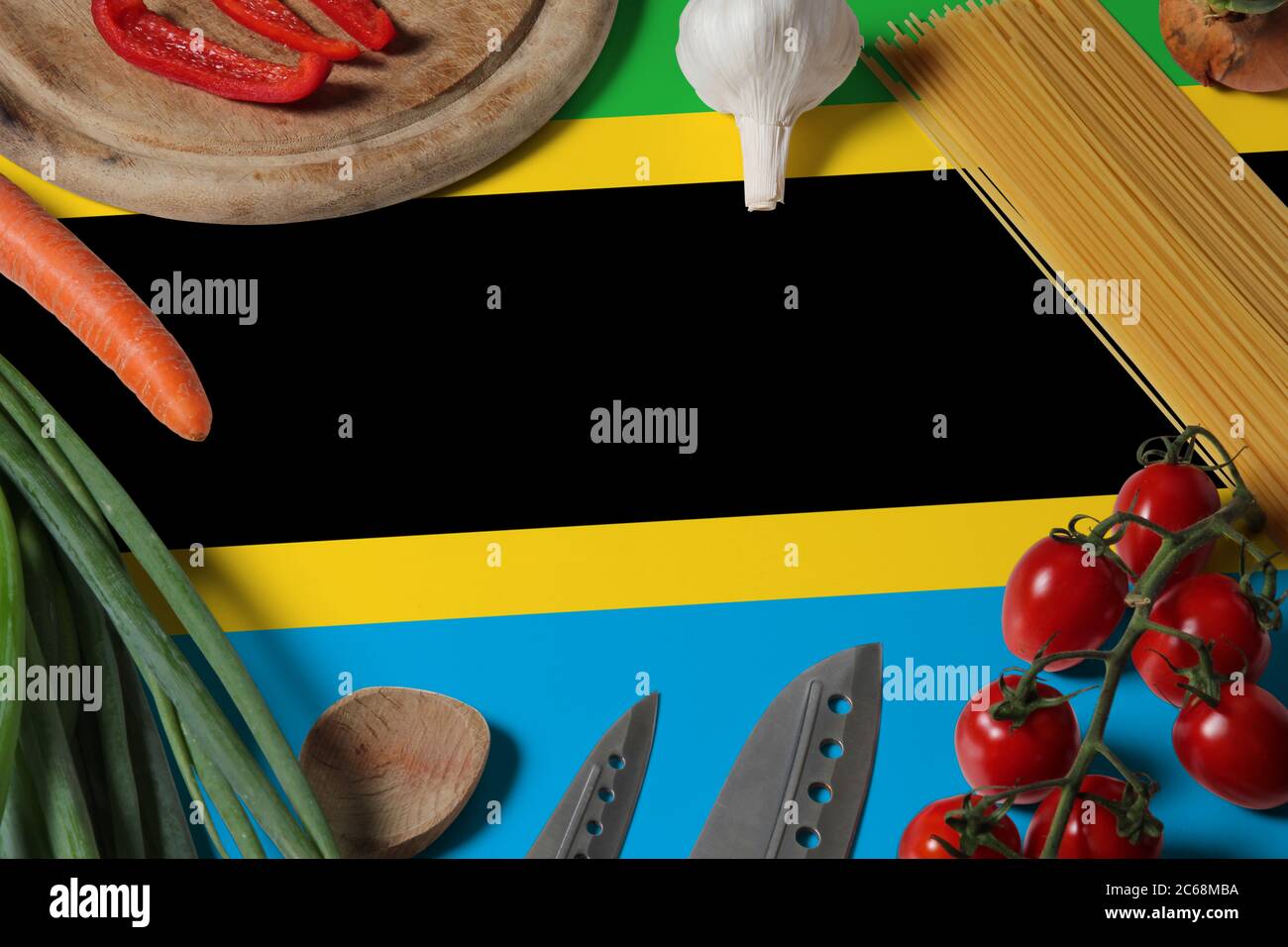 Drapeau tanzanien sur les légumes frais et couteau concept table en bois. Concept de cuisine avec thème de préparation. Banque D'Images