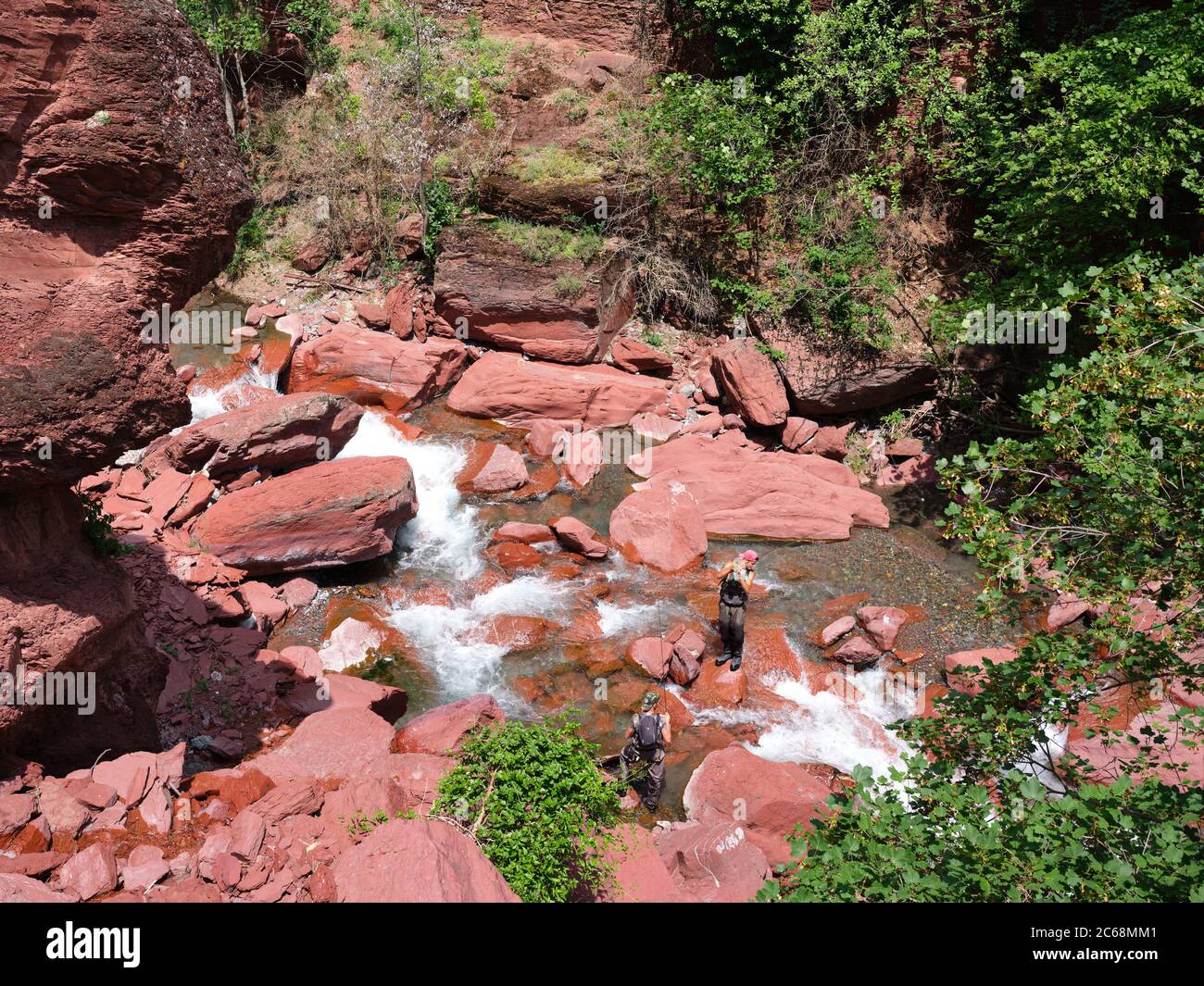 Deux jeunes hommes pêchent à la mouche dans une rivière pittoresque dans un canyon de rochers rouges en pélite. Rivière Cians, Gorges du Cians, Beuil, Alpes-Maritimes, France. Banque D'Images