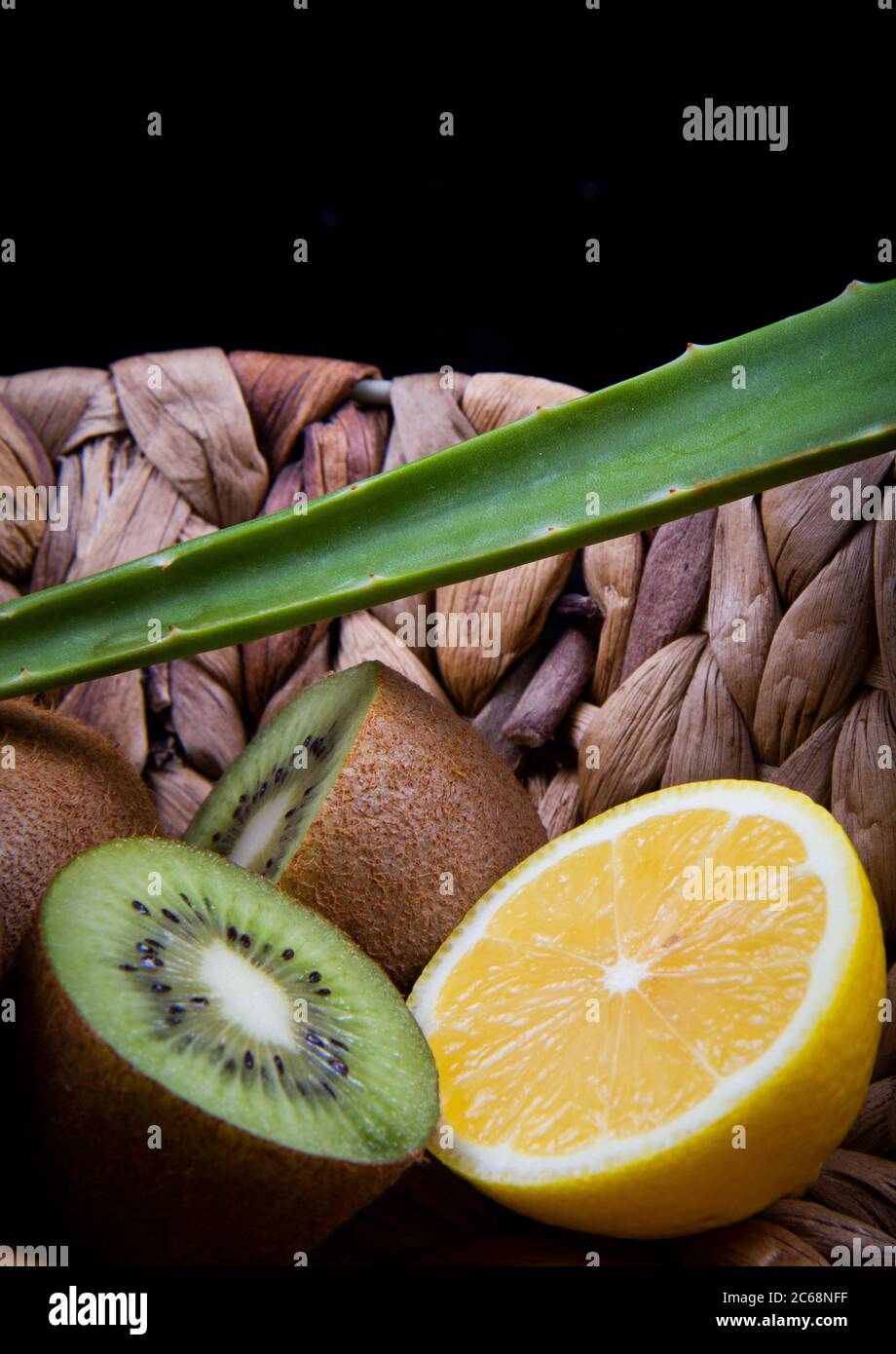 Kiwi et citron aigre et une feuille d'aloe vera dans un panier en bois. Banque D'Images