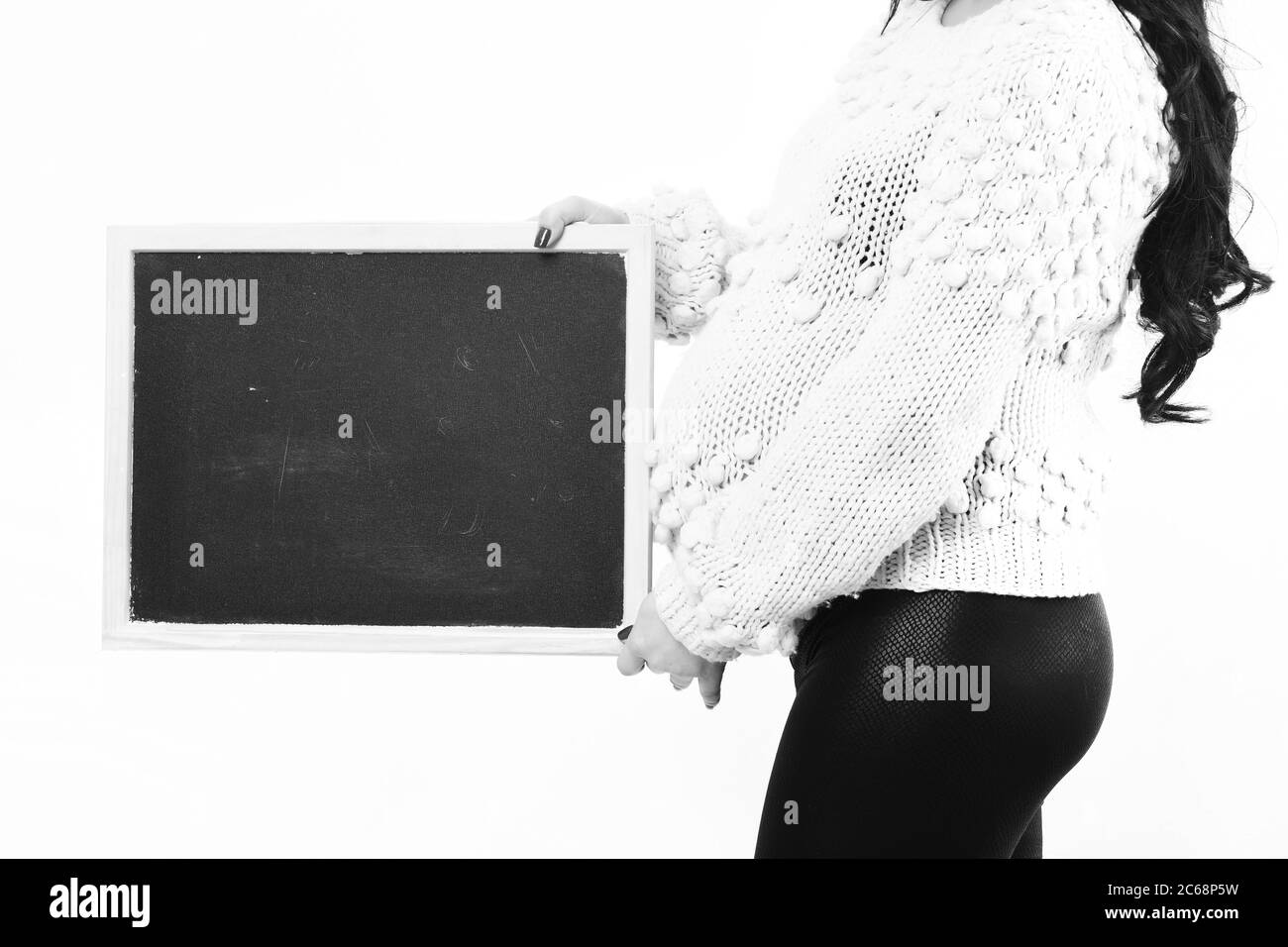 mains féminines de la femme enceinte tenant un pull en tricot noir beige isolé sur fond de studio blanc, espace de copie Banque D'Images