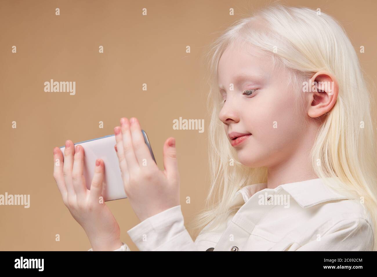 belle albino enfant tenant smartphone blanc dans les mains isolées, fille  avec cheveux blancs et peau regarder l'écran sur le téléphone mobile.  beauté inhabituelle de peo Photo Stock - Alamy