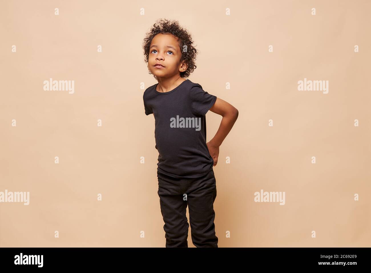Portrait De Petit Garcon Afro Americain Noir Isole Doux Look A Les Cheveux Boucles Portant Un T Shirt Noir Et Un Jean Arriere Plan Beige Isole Photo Stock Alamy