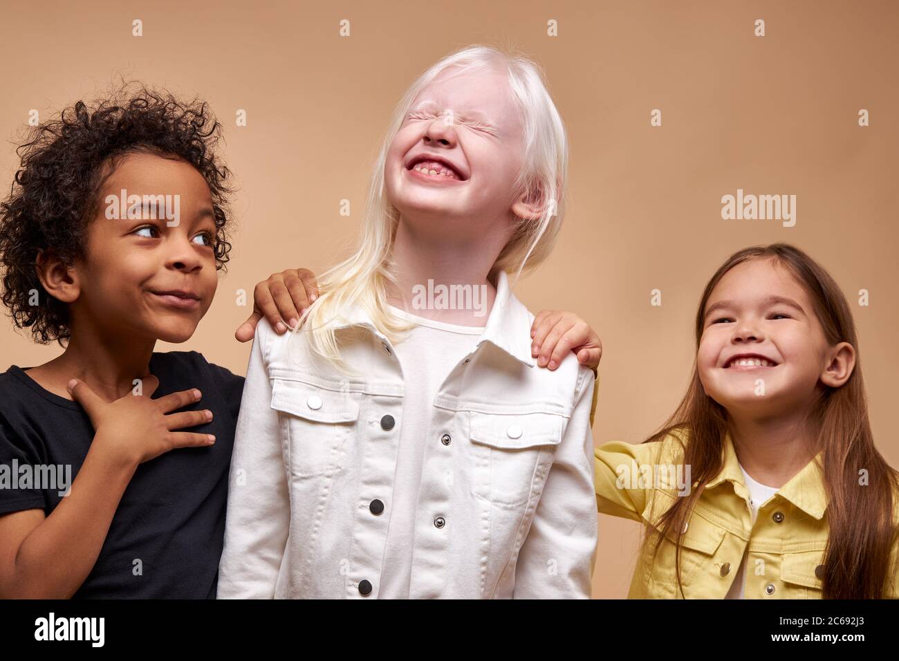 portrait d'adorables enfants divers isolés. les enfants noirs afro, albinos et européens se tiennent ensemble, l'amitié étroite entre eux. les gens diverent Banque D'Images