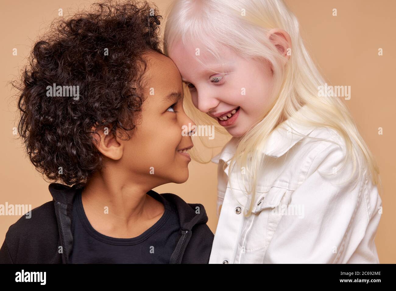 une amitié étroite entre deux enfants de différentes nationalités, belle albinos caucasienne fille et africain garçon avec des cheveux bouclés, ils sont embrassant Banque D'Images