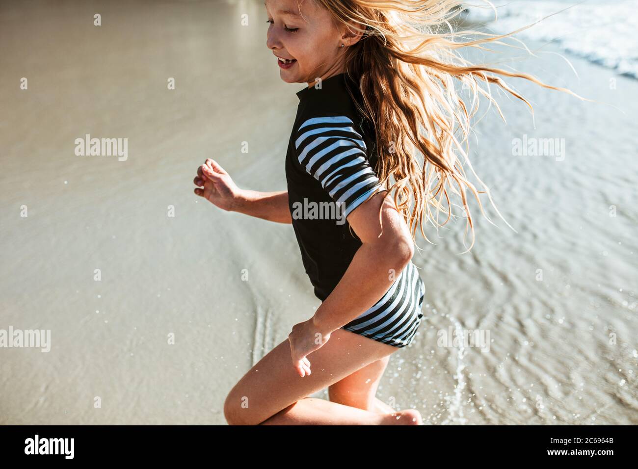 Jolie fille qui court dans l'eau à la plage. Petite fille s'amuser pendant les vacances d'été à la plage. Banque D'Images