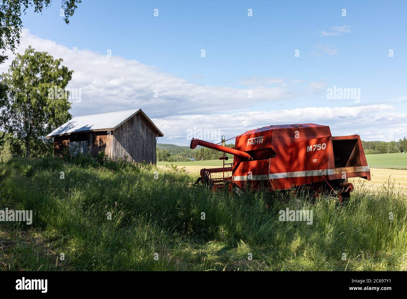 Ancienne grange et moissonneuse-batteuse à l'ancienne, Fahr M750, au champ d'Orivesi, en Finlande Banque D'Images