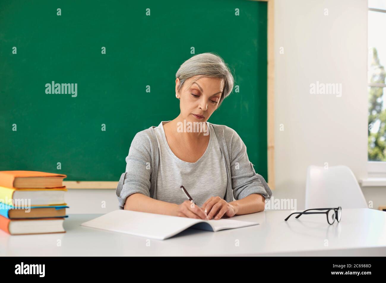 Enseignant enseigne. Femme enseignante regardant la caméra à la leçon dans la salle de classe. Banque D'Images