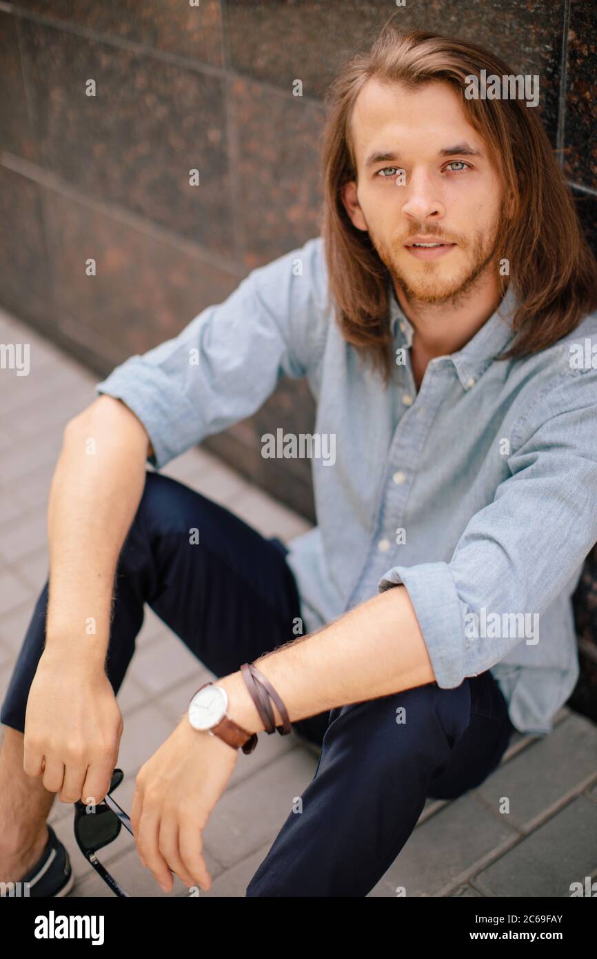 Portrait d'un beau homme assis au sol, appuyé contre un mur, la Russie Banque D'Images
