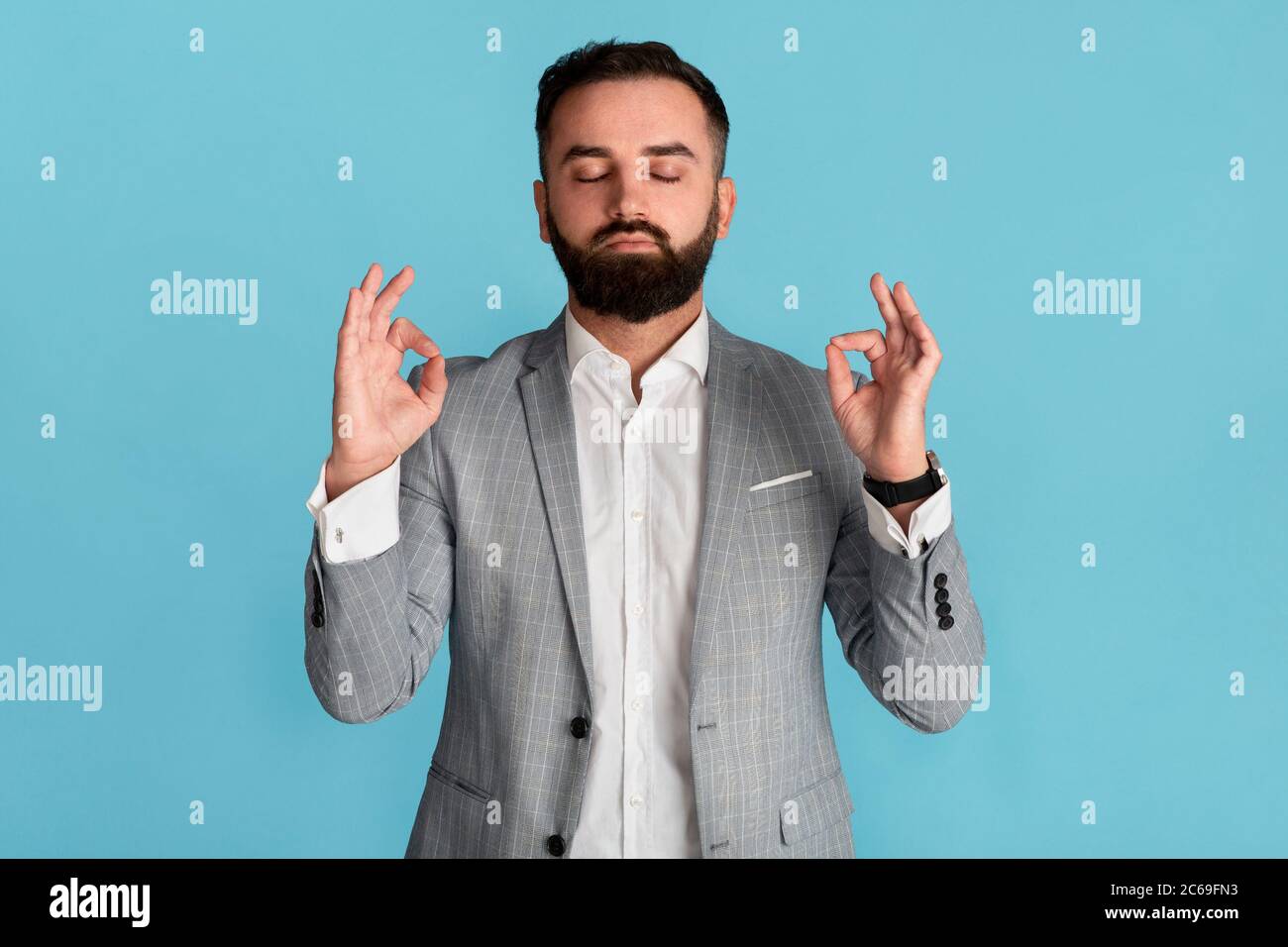 Gestion du stress. Jeune employé de bureau avec les yeux fermés méditant sur fond bleu Banque D'Images