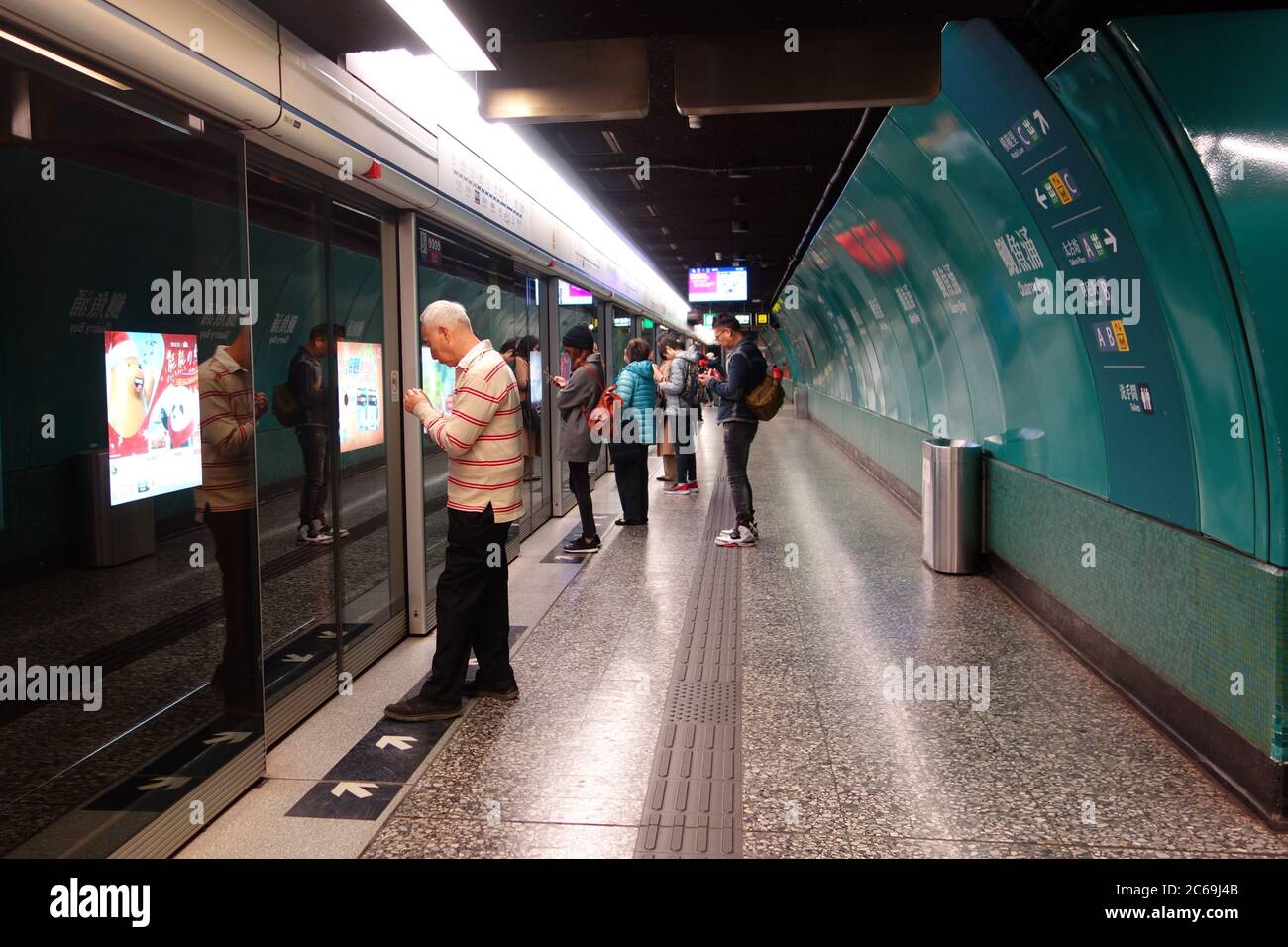 Les gens attendent derrière les portes coulissantes automatiques de la station de métro de Hong Kong. Banque D'Images
