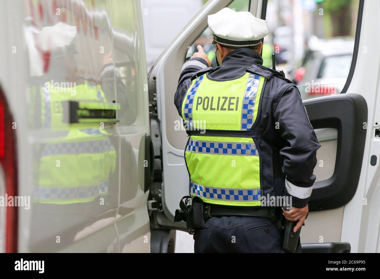 24 avril 2020, Hambourg: Un policier est en service dans un poste de contrôle de la police à Max-Brauer-Allee. Il tient une main sur son arme de service. La police de Hambourg a vérifié le respect par les conducteurs du district d'Altona de l'interdiction de la conduite de diesel. Il y a une interdiction de conduire pour les voitures et les camions diesel plus anciens à près de 600 mètres de Max-Brauer-Allee. Les infractions seront passibles d'amendes. Photo : marques de bodo/dpa Banque D'Images