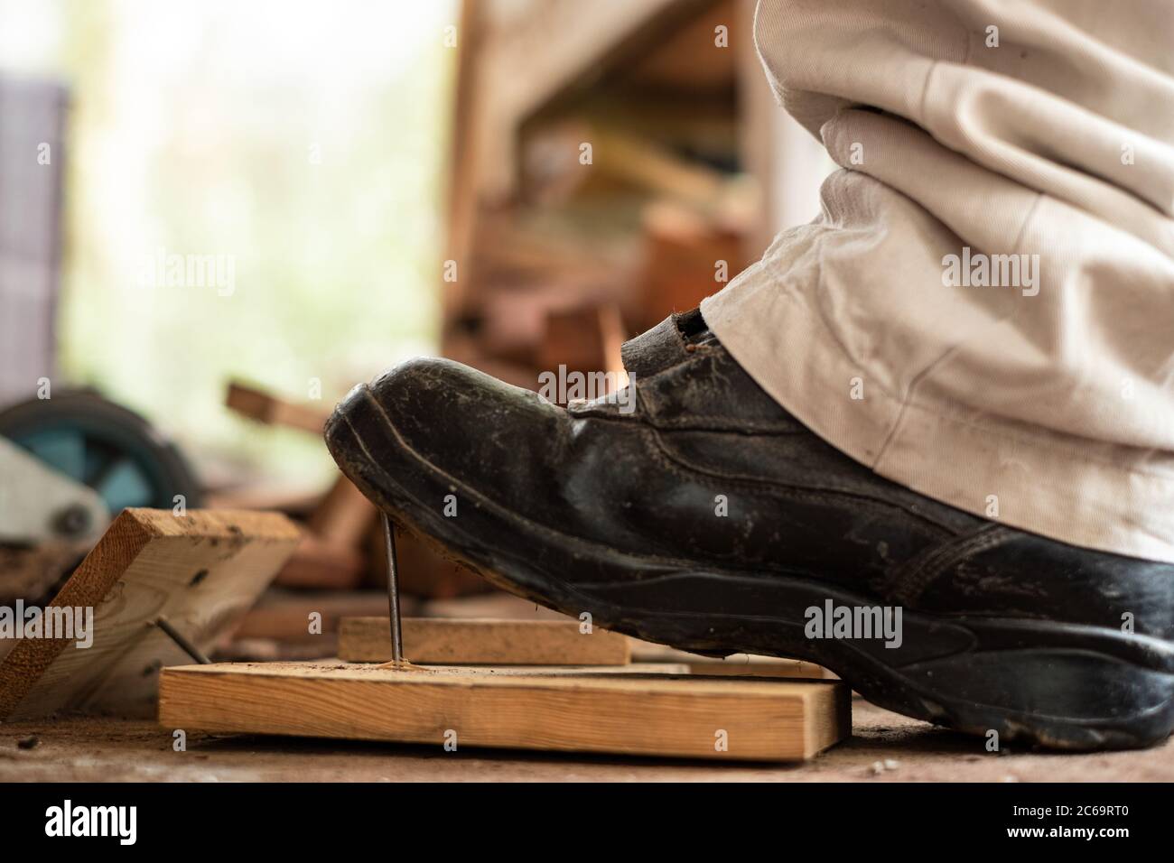Travailleur dans des chaussures de sécurité qui marche sur des clous à bord  de bois dans la zone de construction Photo Stock - Alamy