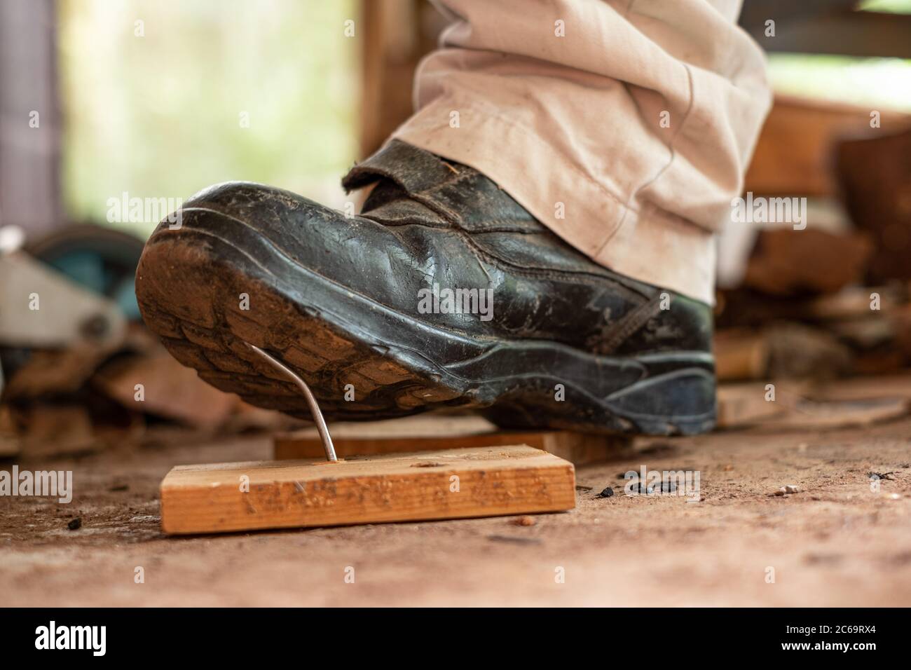 Travailleur dans des chaussures de sécurité qui marche sur des clous à bord  de bois dans la zone de construction Photo Stock - Alamy