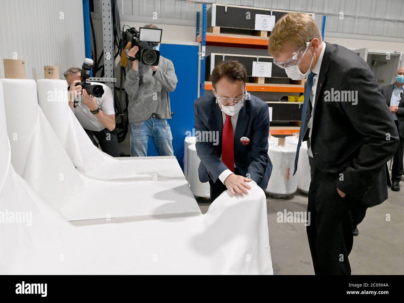 08 juillet 2020, Schleswig-Holstein, Neumünster: Daniel Günther (CDU, r), Premier ministre du Schleswig-Holstein, est donné une explication de divers matériaux pour la production de masques protecteurs par Rainer Straub, Directeur général d'Oerlikon Nonwoven. Ici, Oerlikon produit des machines pour la fabrication de matériaux pour la production de nontissés et produit des couches protectrices pour les masques eux-mêmes. Photo: Carsten Rehder/dpa Banque D'Images