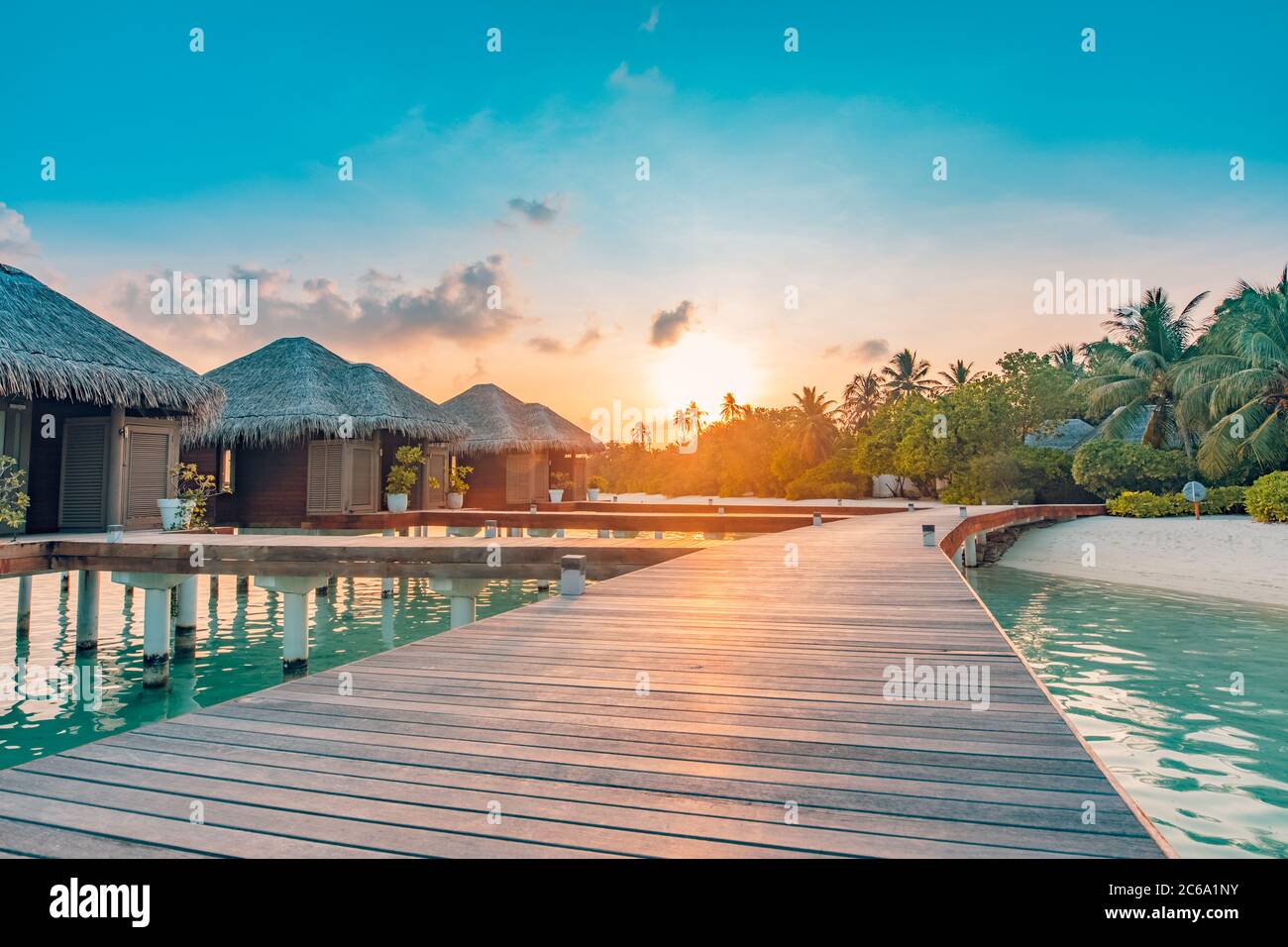 Coucher de soleil sur l'île des Maldives, complexe de villas de luxe sur l'eau et jetée en bois. Magnifiques nuages de ciel et fond de plage pour vacances d'été voyage Banque D'Images