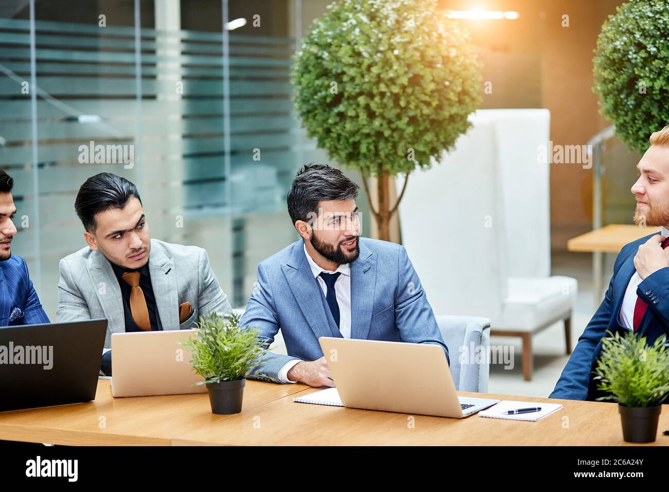 Les jeunes politiciens mènent des négociations sur un nouveau projet, un nouveau contrat, en utilisant des ordinateurs portables, assis sur une table en bois. Arrière-plan Office Banque D'Images