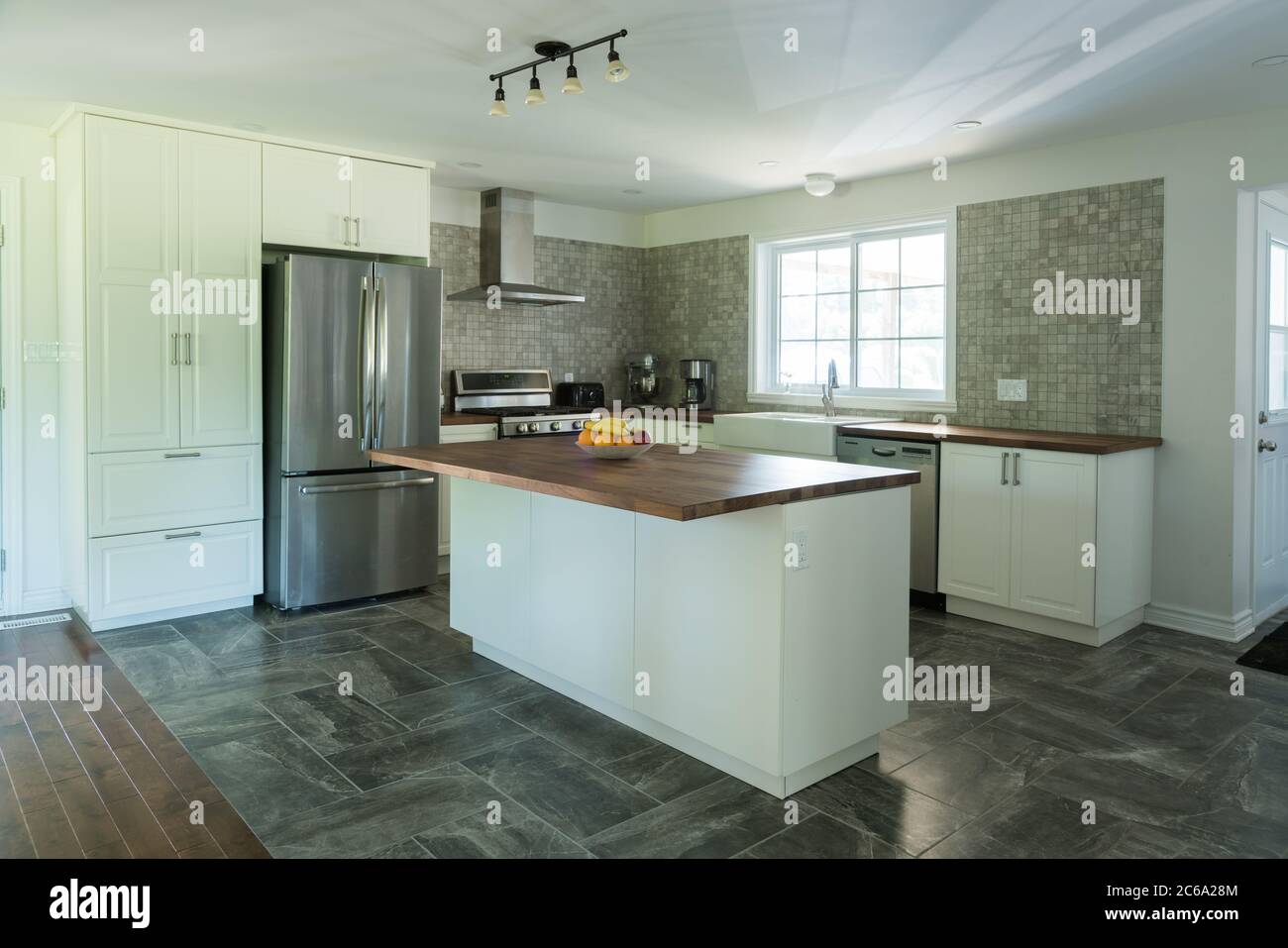 Nouvelle cuisine grise et blanche avec carrelage en marbre, appareils électroménagers et bancs en bois Banque D'Images