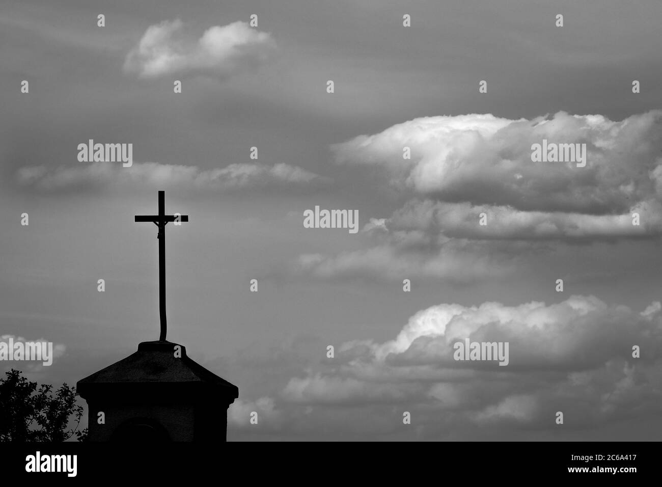 Silhouette d'un ancien sanctuaire en bordure de route dans une campagne polonaise contre un ciel nuageux avec espace de copie, image monochrome Banque D'Images