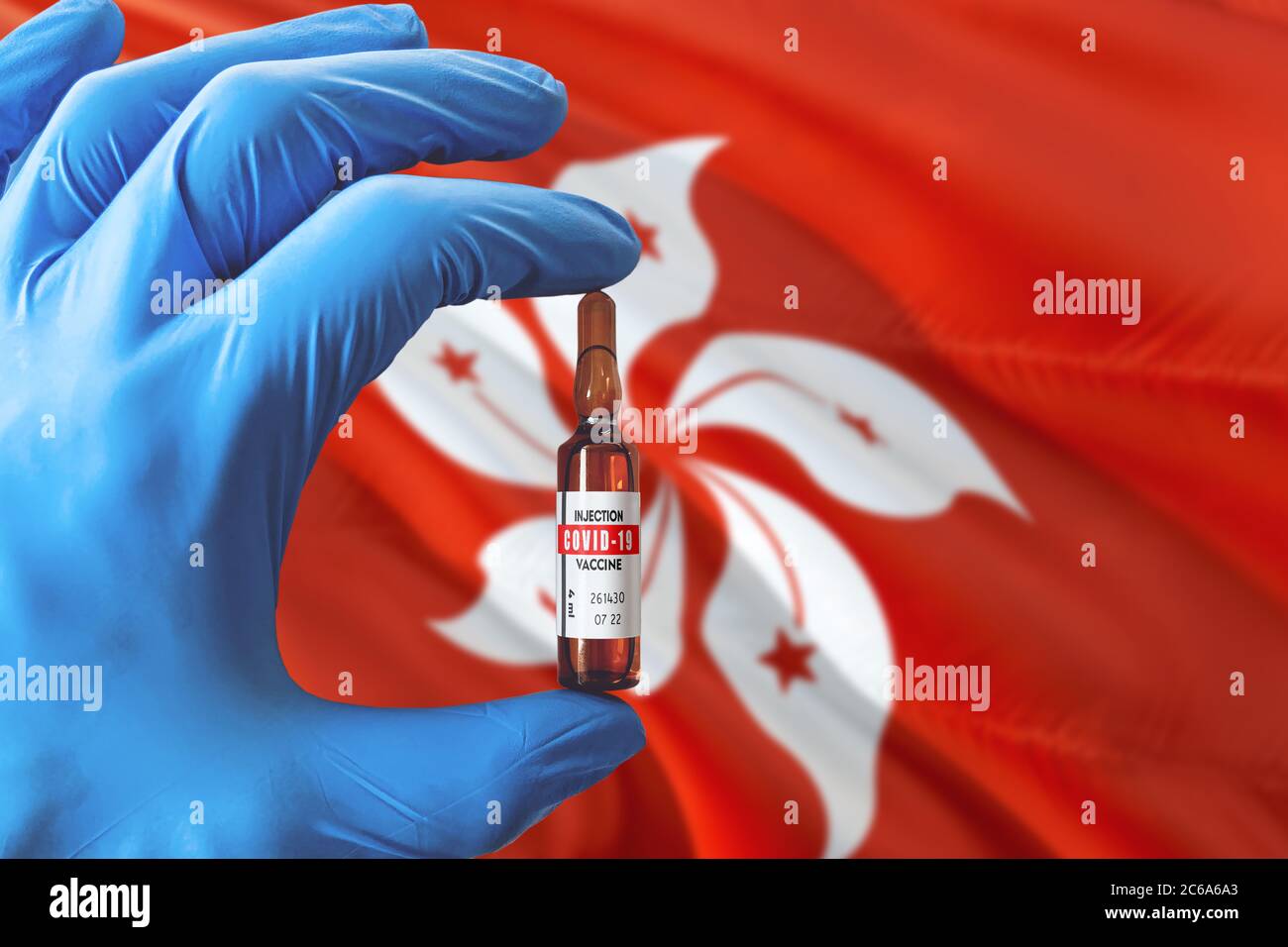 Drapeau de Hong Kong avec le concept Covid-19 du coronavirus. Médecin avec des gants médicaux de protection bleus tenant une bouteille de vaccin. Virus épidémique, COV-19, Corona Banque D'Images