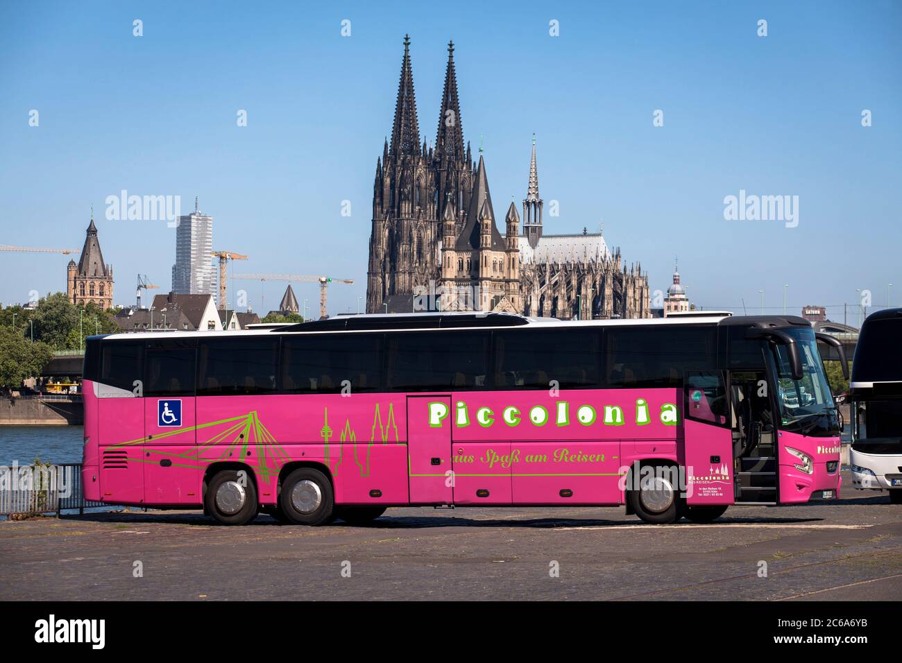 Autocar de couleur rose sur les rives du Rhin à Deutz, vue sur la cathédrale, Cologne, Allemagne. Pinkfarbener Reisebus am Rheinufer à Deutz, Blick z Banque D'Images