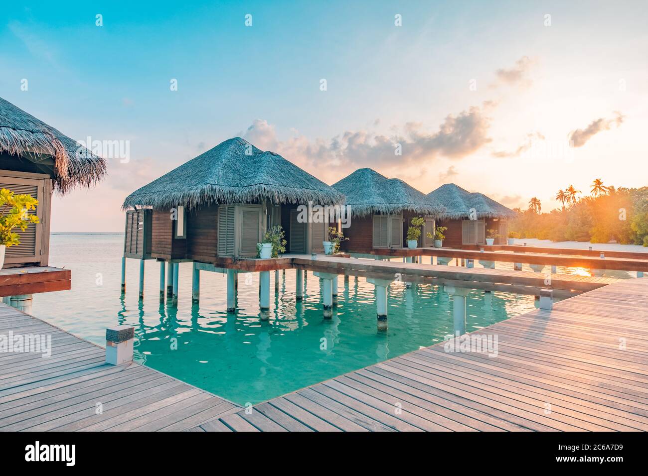 Coucher du soleil sur l'île des Maldives, l'eau de luxe villas resort et jetée en bois. Beau Ciel et nuages et fond de plage pour l'été vacances Banque D'Images