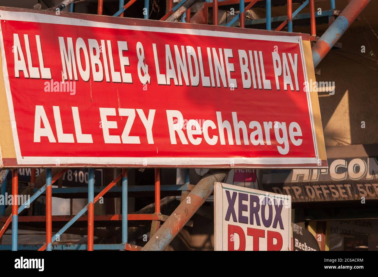 Un panneau/palissade à l'extérieur d'un établissement d'affaires en Inde offrant un dispositif de recharge de téléphone mobile. Le mot « recharger » est mal orthographié. Banque D'Images