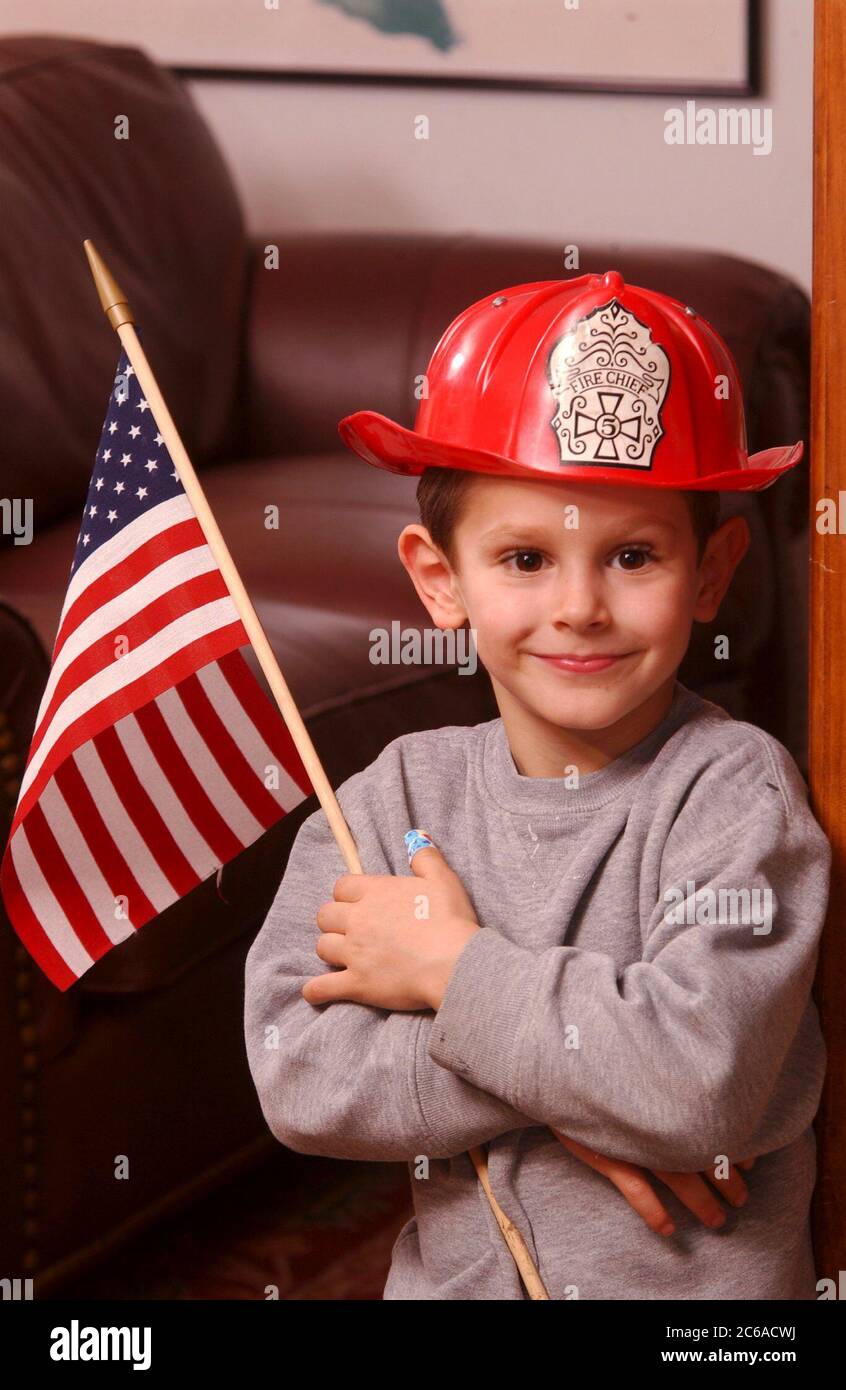 Austin, Texas États-Unis, 31 janvier 2002 : Robin David Daemmrich, 5 ans, pose avec un casque de pompier et un drapeau américain pendant le jeu. Il dit qu'il veut être un brave pompier quand il sera grand. ©Bob Daemmrich Banque D'Images