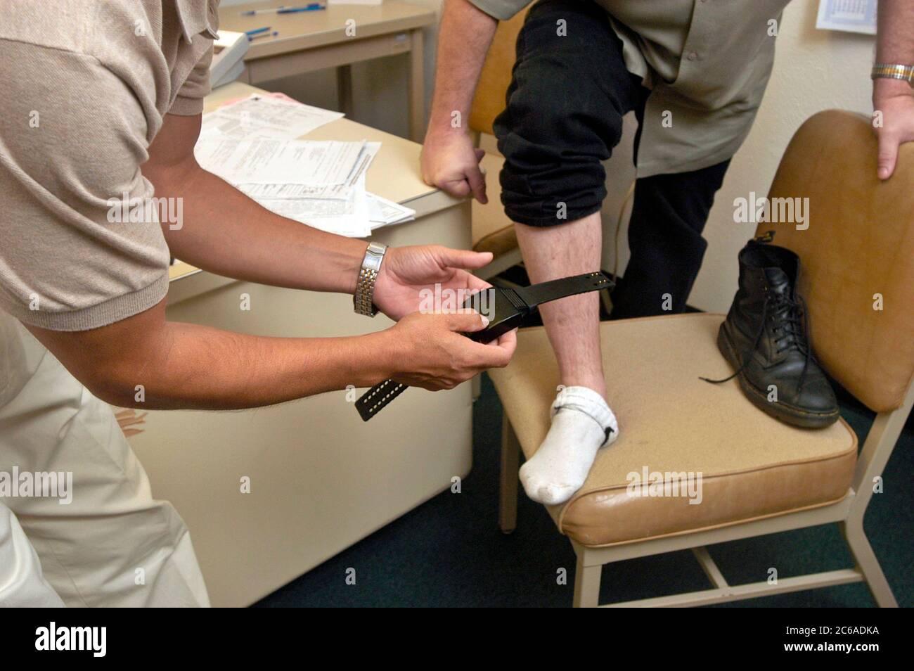 Austin, Texas États-Unis, 5 septembre 2003 : un agent de libération conditionnelle du Texas attache un dispositif de surveillance électronique à la cheville d'un détenu libéré sous condition. ©Bob Daemmrich Banque D'Images