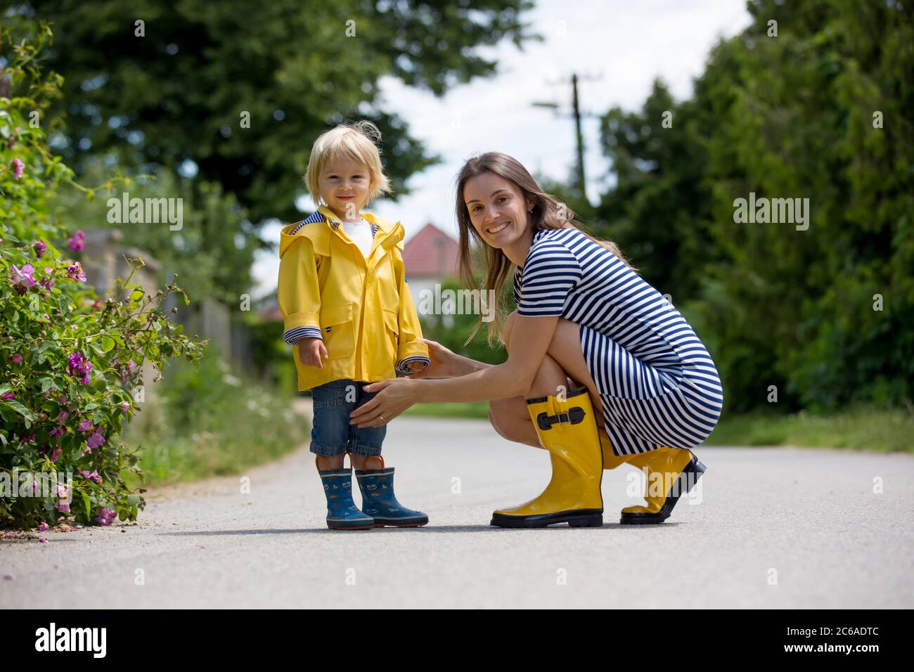 Mère et tout-petit enfant, garçon, jouant sous la pluie, portant des bottes et des manteaux de pluie Banque D'Images