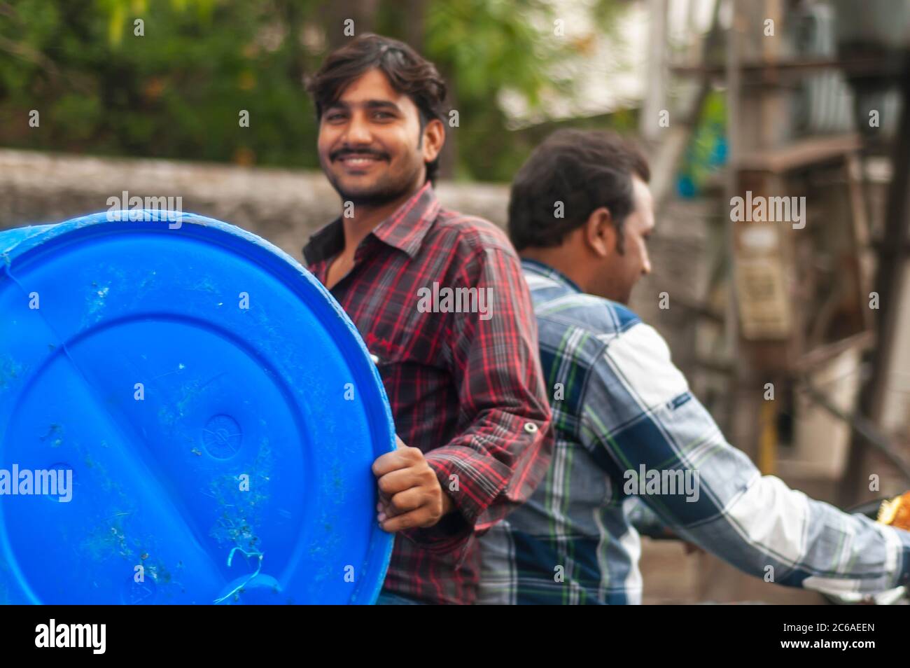 Un Indien qui a fait un pilion en arrière tout en portant un tambour. C'est un exemple de « jugaad » ou une solution non conventionnelle pour transporter un tambour sur une moto. Banque D'Images