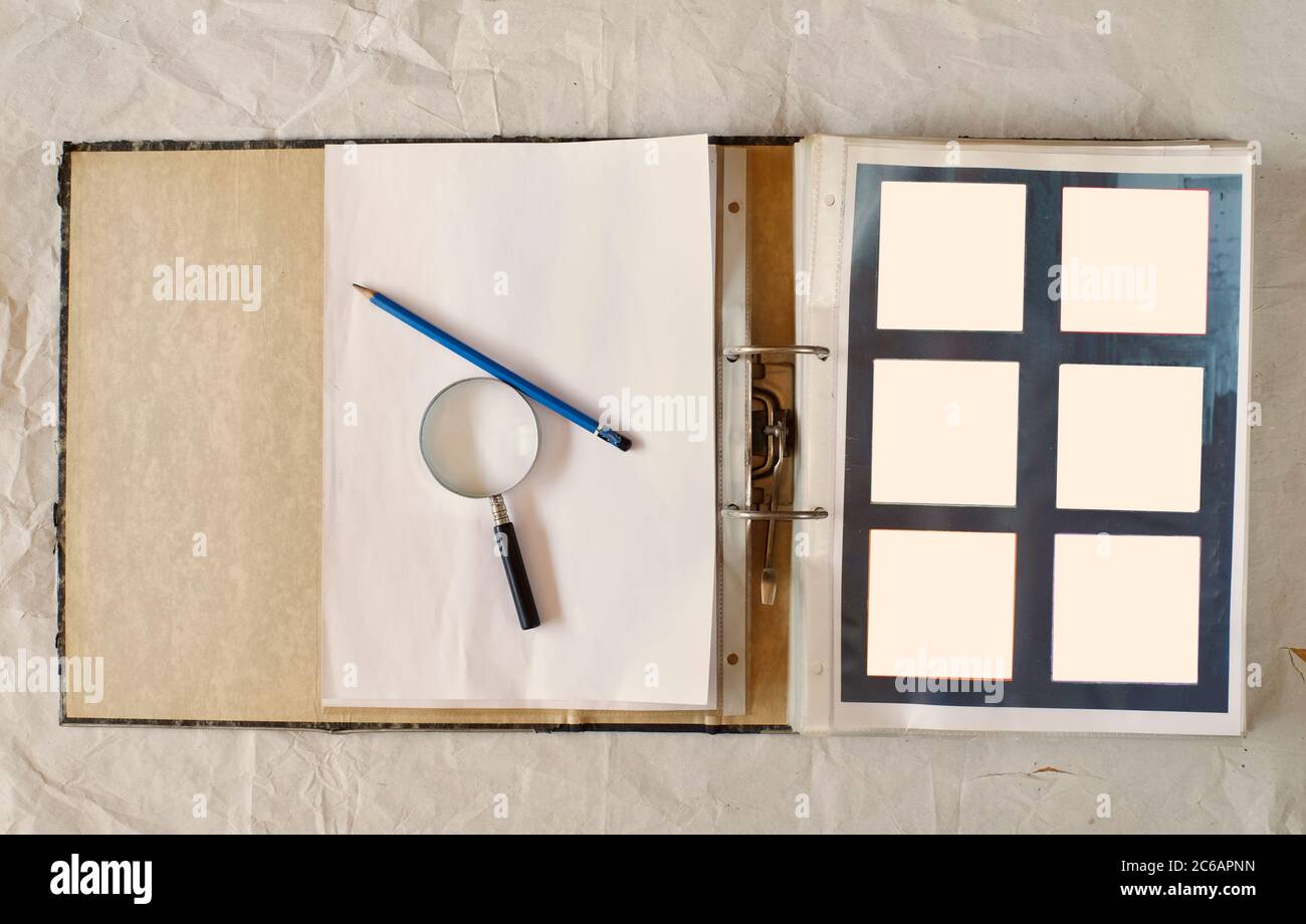 Dossier de fichiers ouvert avec cadres photo vides, loupe et stylo, mise à plat, maquette, espace de copie Banque D'Images
