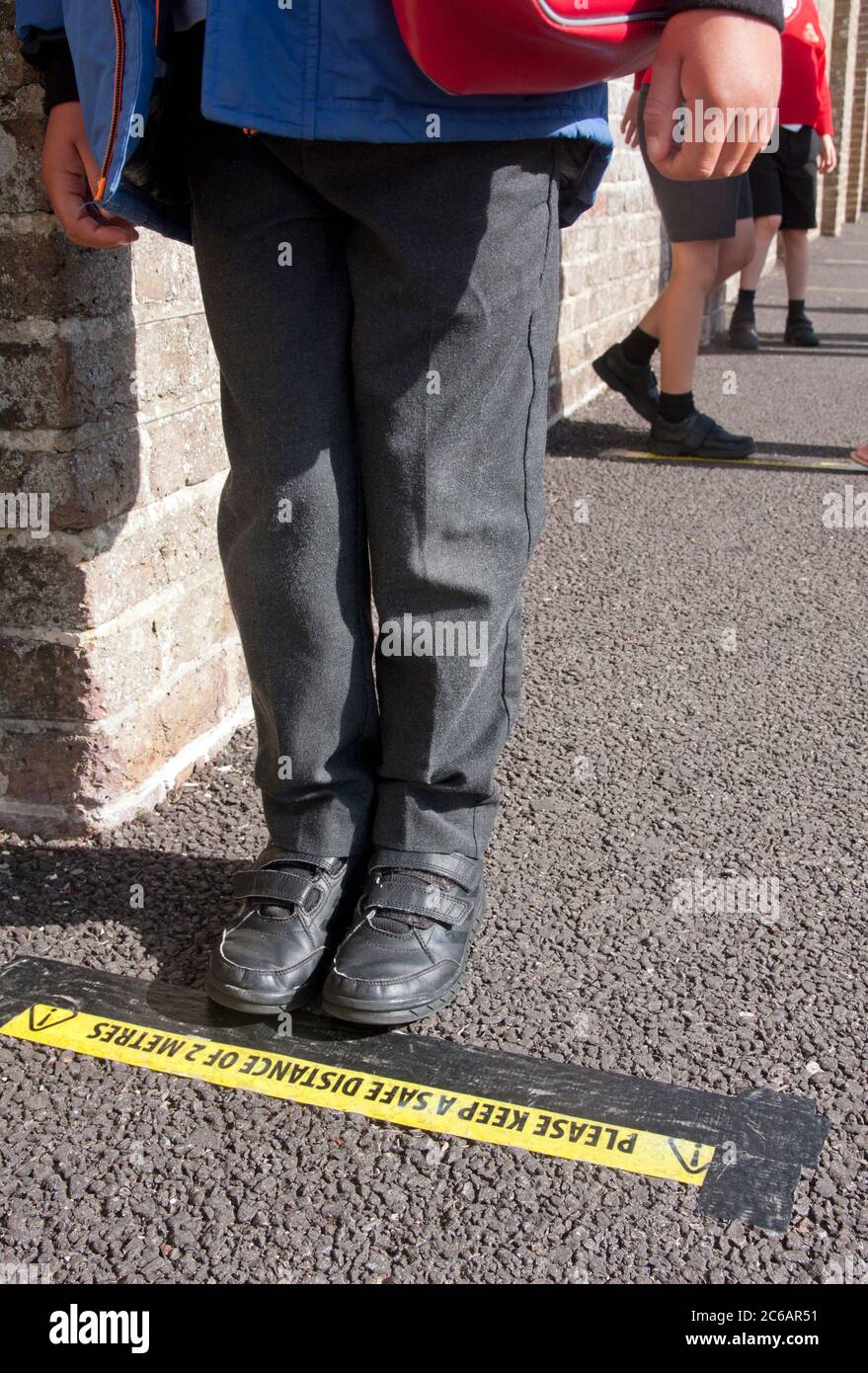 Enfant d'école primaire debout sur la ligne de distance sociale pendant l'épidémie Covid-19 de 2020, Angleterre Banque D'Images