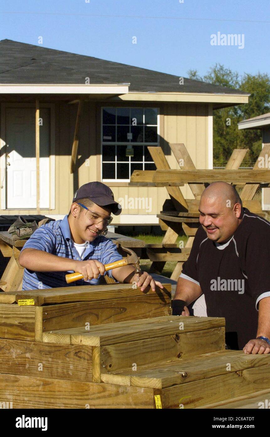 San Juan, Texas États-Unis, décembre 17 2004 : père hispanique et fils de 15 ans donnent leur temps pour travailler sur les escaliers pour une nouvelle maison dans un projet de logement à faible revenu. La famille a acheté une maison par l'entremise de Proyecto Azteca, un programme d'aide au logement dans lequel les familles contribuent des heures de bénévolat en échange de l'aide de Proyecto Azteca pour financer l'achat d'une maison. Modèle validé. ©Bob Daemmrich Banque D'Images