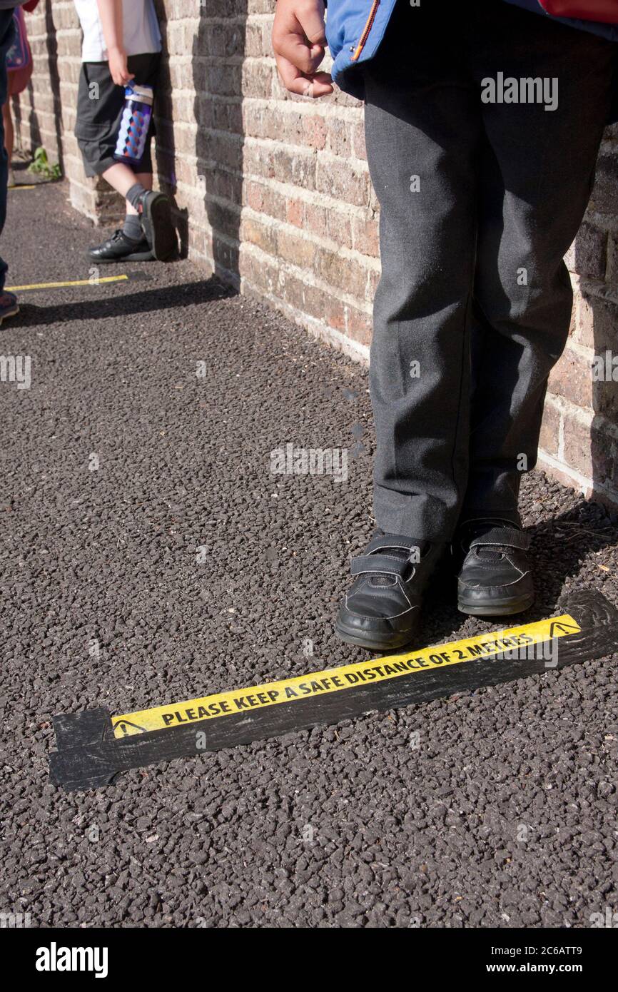 Enfant d'école primaire debout sur la ligne de distance sociale pendant l'épidémie Covid-19 de 2020, Angleterre Banque D'Images