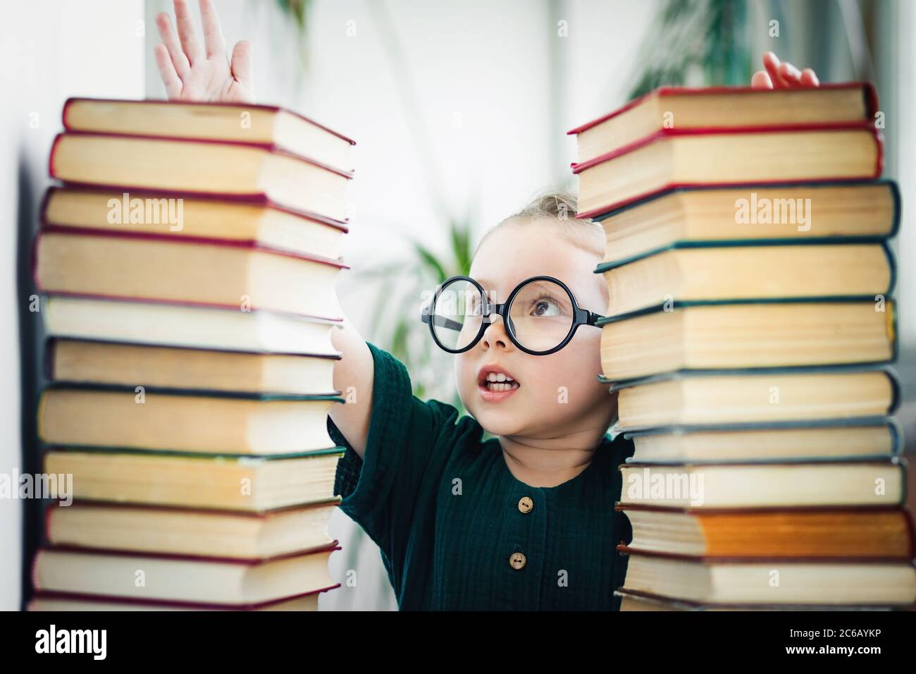 Le génie de petite fille d'âge préscolaire lit une tonne de livres.  Éducation des enfants et développement précoce concept Photo Stock - Alamy