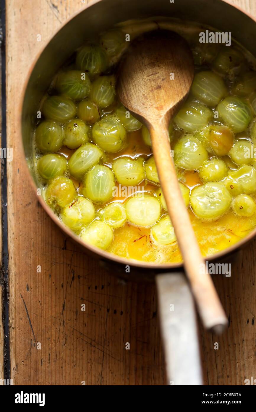 Faire bouillir la baie de gooseberry avec du safron et du miel. Préparer de la compote de groseilles à maquereau Banque D'Images