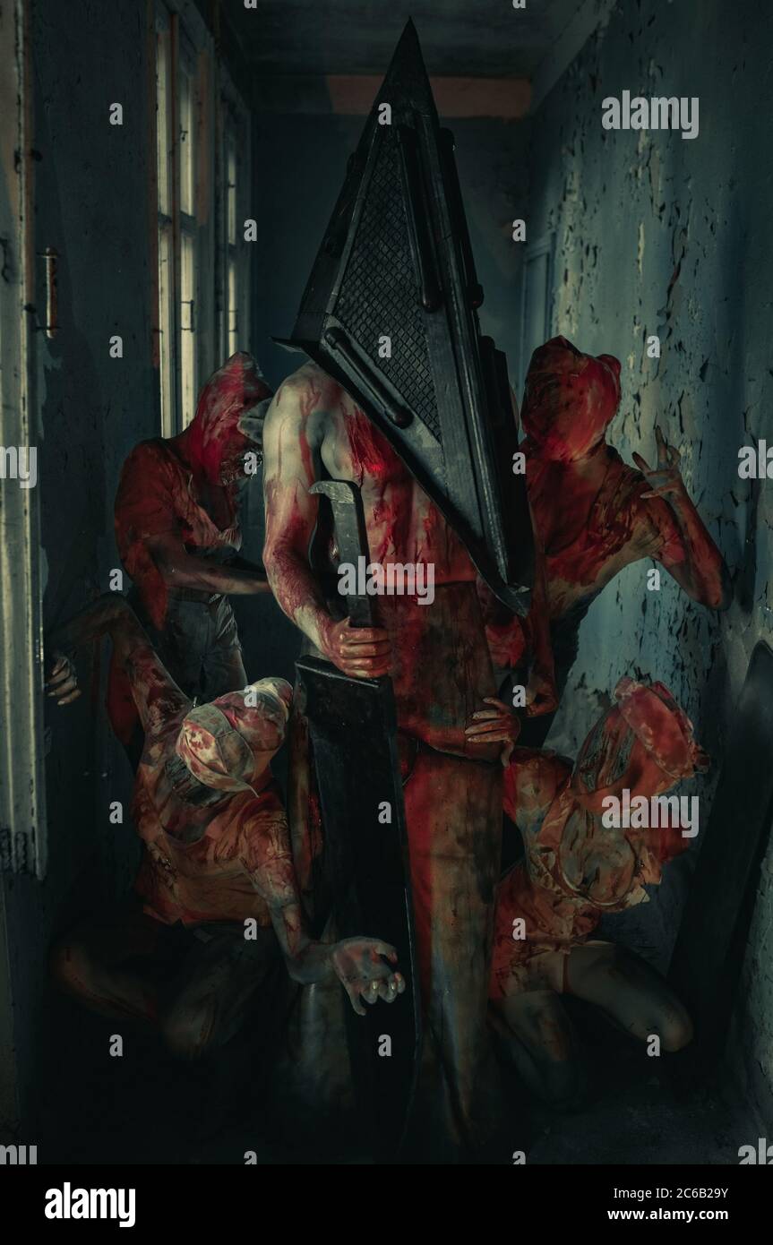 Les cojoueurs à l'image de monstres sanglants et bourreau se tiennent dans  la pièce sombre Photo Stock - Alamy
