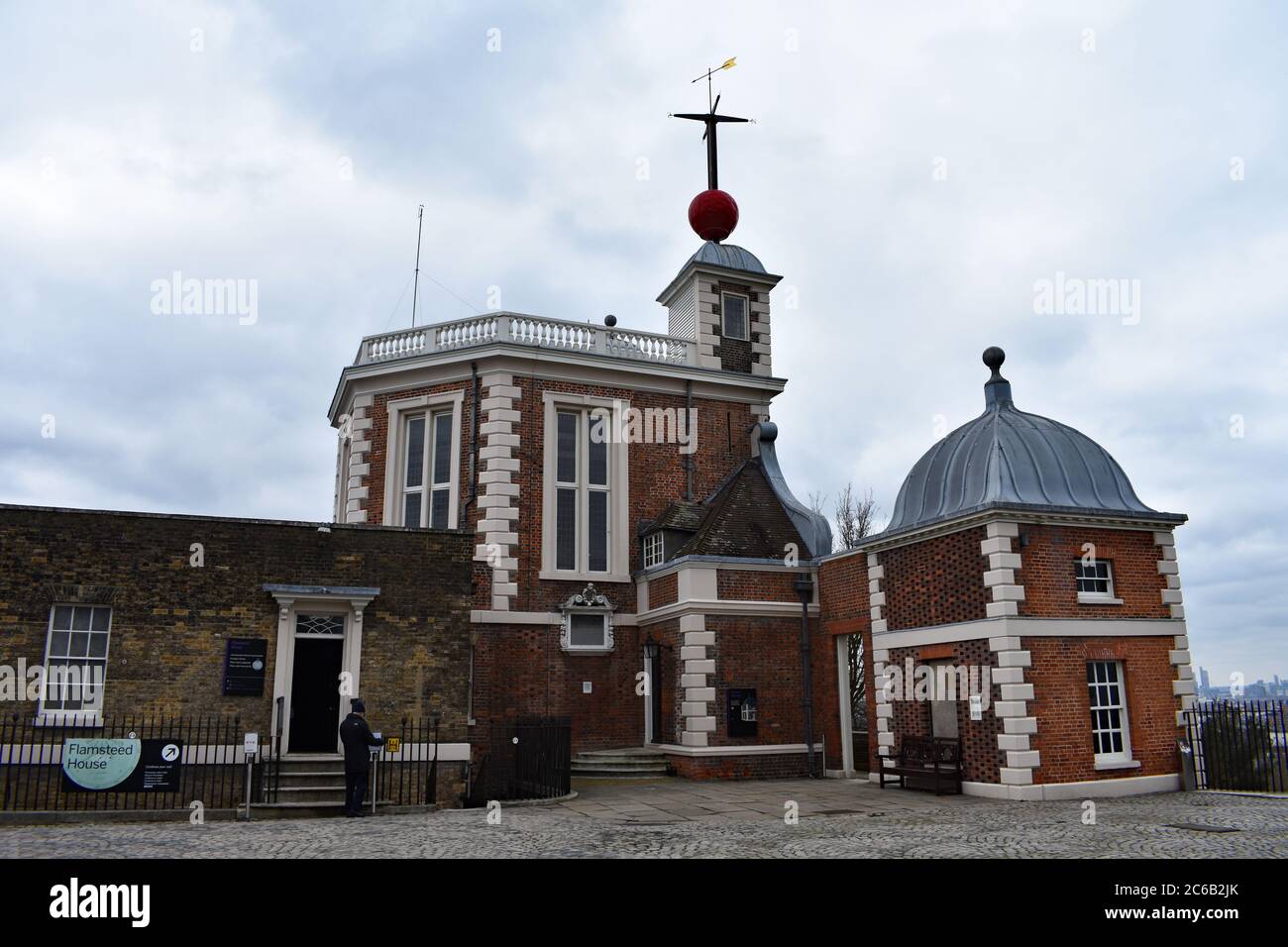 Un visiteur sur le point d'entrer dans la Maison flammé à l'Observatoire royal de Greenwich Park. Une boule de temps rouge et une girouette au-dessus de la salle Octagon. Banque D'Images