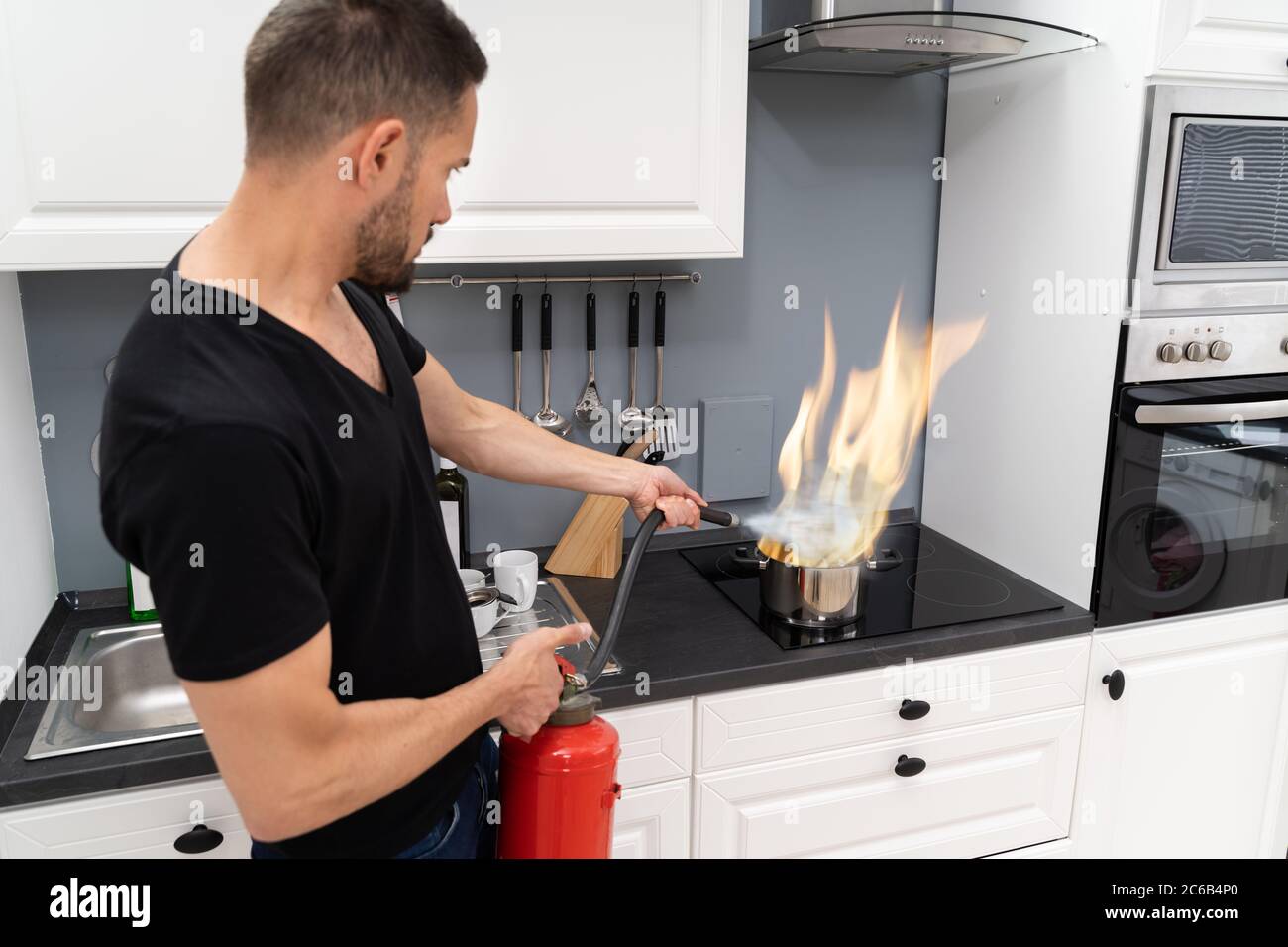 L'homme à l'aide d'extincteur pour feu stop sur la gravure de casserole dans la cuisine Banque D'Images