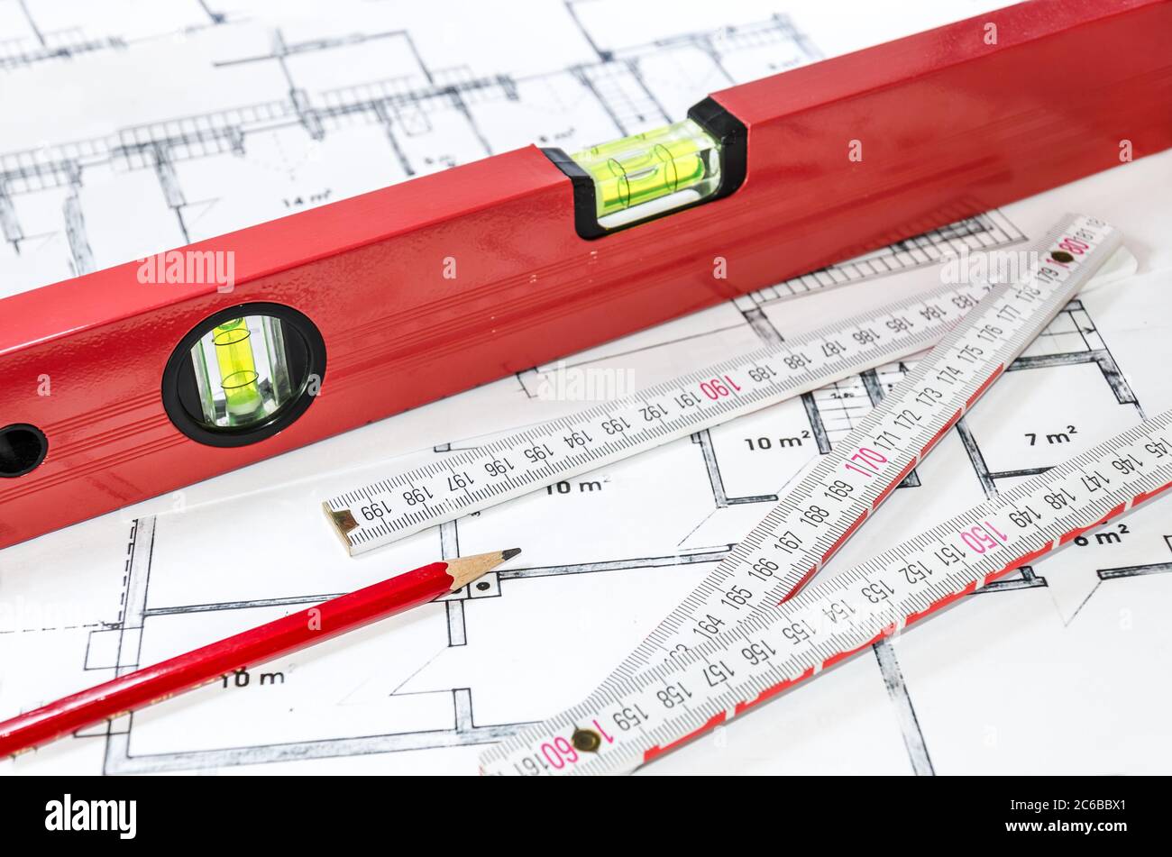 Niveau à bulle, crayon et baguette sur un plan de construction Banque D'Images