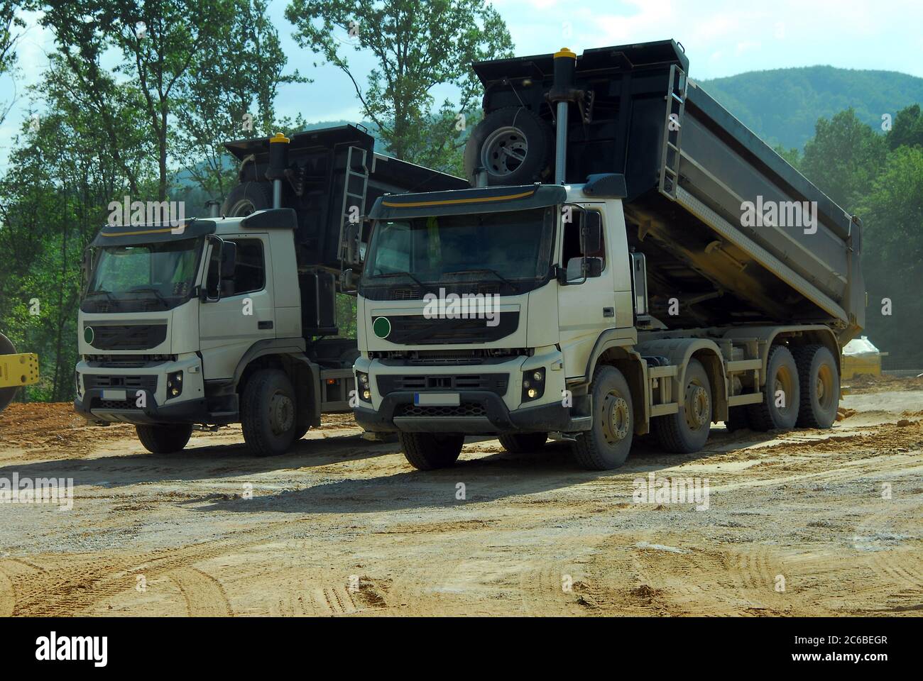 deux grands camions benne basculante en service, deux grands camions benne basculante déchargeant la terre sur le site Banque D'Images