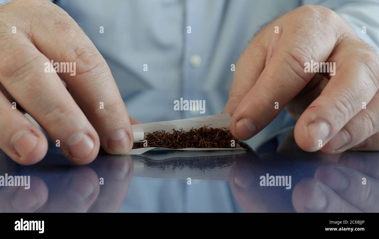 Fume rouler une cigarette faite à la main en utilisant du papier à cigarettes un filtre et du tabac Banque D'Images