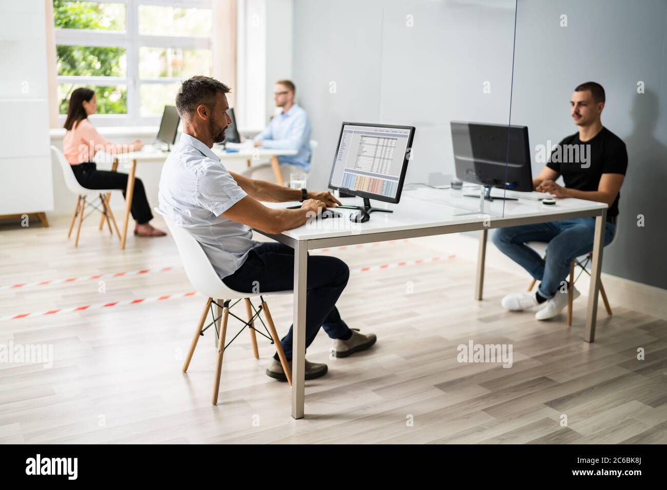 Les employés d'entreprise ont pris des distances sociales en utilisant des gardes d'éternuement dans le bureau Banque D'Images