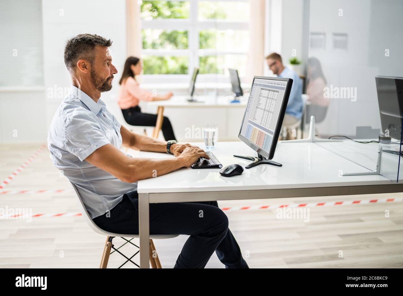 Les employés d'entreprise ont pris des distances sociales en utilisant des gardes d'éternuement dans le bureau Banque D'Images