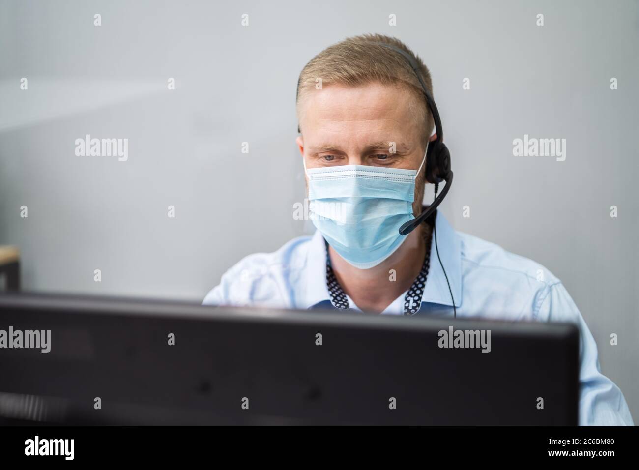 Opérateur téléphonique du centre d'appels au bureau portant un masque facial Banque D'Images